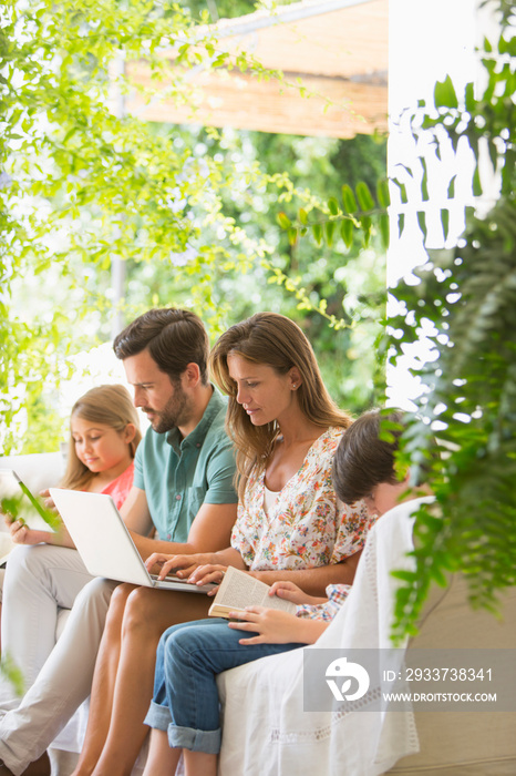 Family relaxing with book and laptop on patio