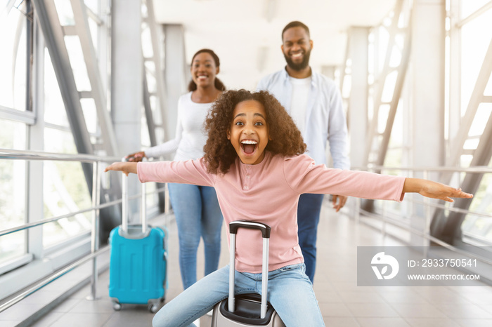 Happy black parents traveling with daughter, standing in airport