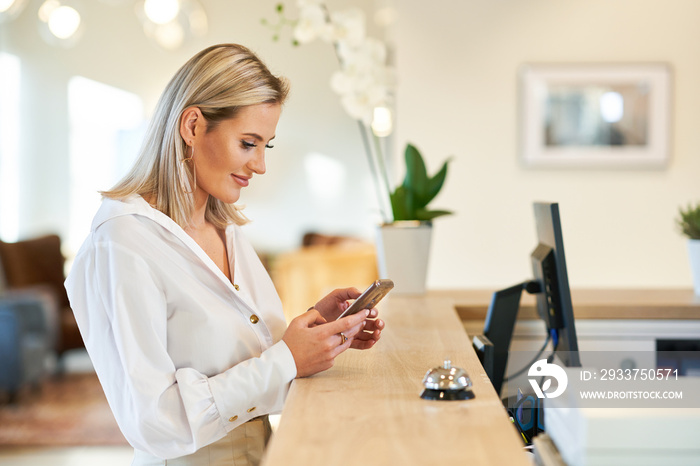 Businesswoman using smartphone at hotel front desk