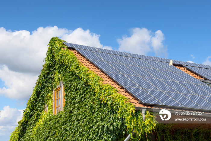 Hausdach mit Solarplatten vor blauem Himmel