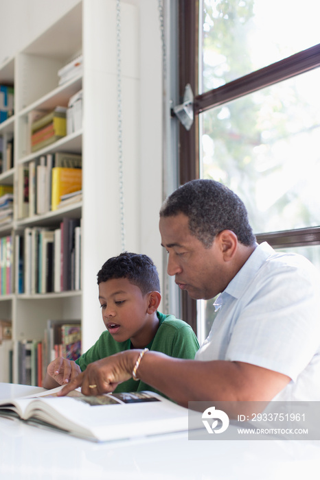 Grandfather helping grandson with homework at table