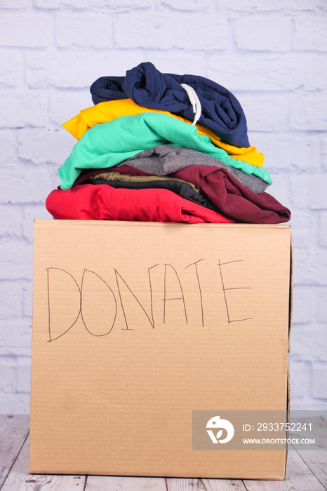 Donation box with donation clothes on a wooden table .