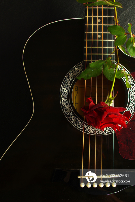 Acoustic black guitar and red rose.