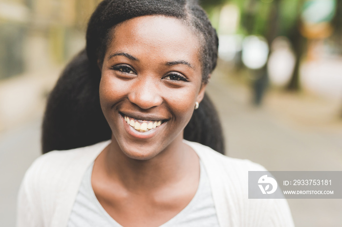 Young beautiful black woman outdoor in the city, looking at camera smiling - happiness, carefree, se