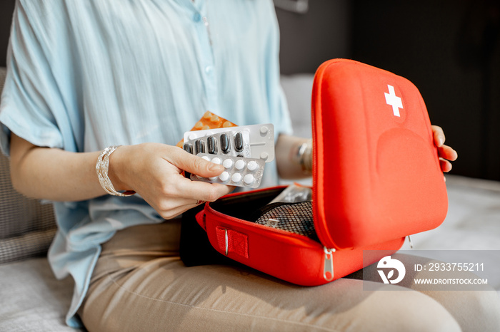 Woman taking pills from the first aid kit, close-up with no face