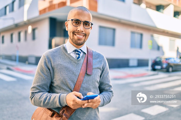 年轻的非裔美国商人在城市里用智能手机开心地微笑着。