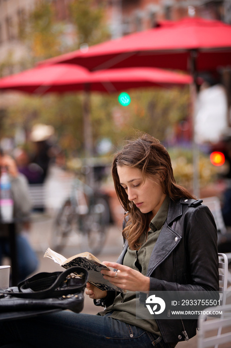 Young woman reading book in outdoor cafe