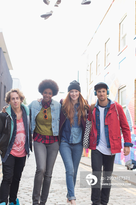 Portrait confident young friends walking on city street