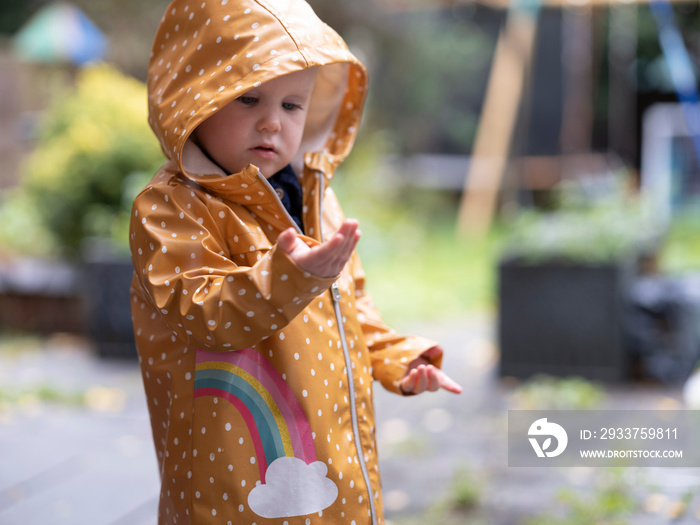 Girl wearing raincoat playing outdoors in rain�