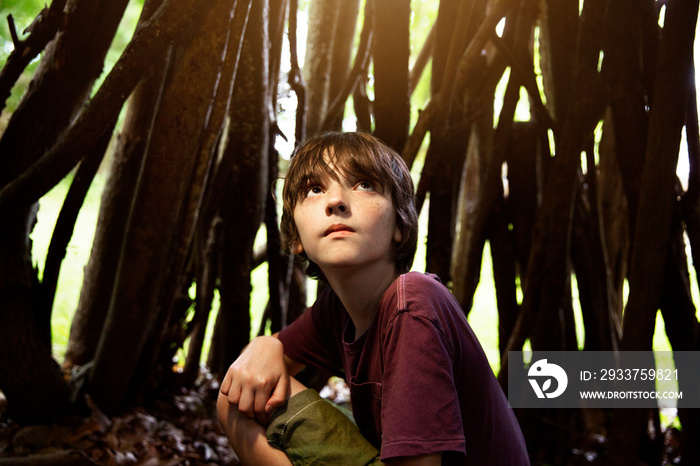 Boy hiding in wooden sticks construction