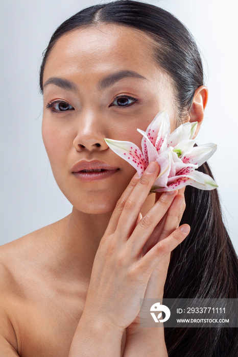 Studio portrait of woman holding white and�purple lily flower