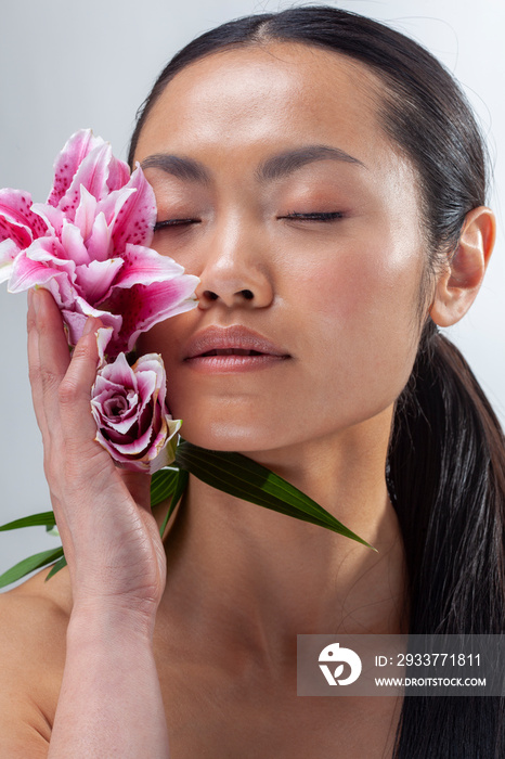 Studio portrait of woman holding white and�purple lily flower