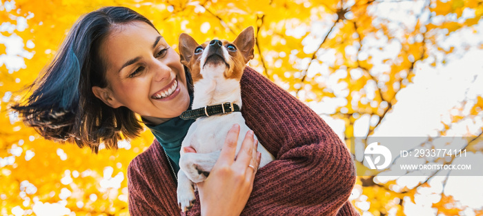 Portrait of young happy woman with little cute dog in park