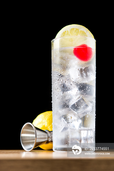 Classic Tom Collins cocktail on wooden table and black background