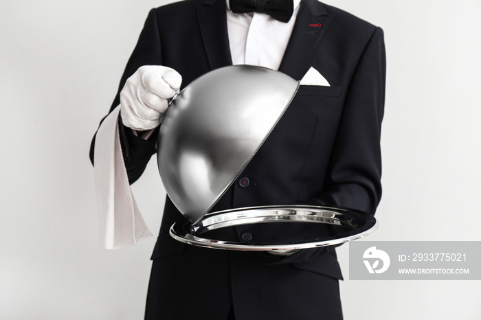 Waiter with tray and cloche on light background