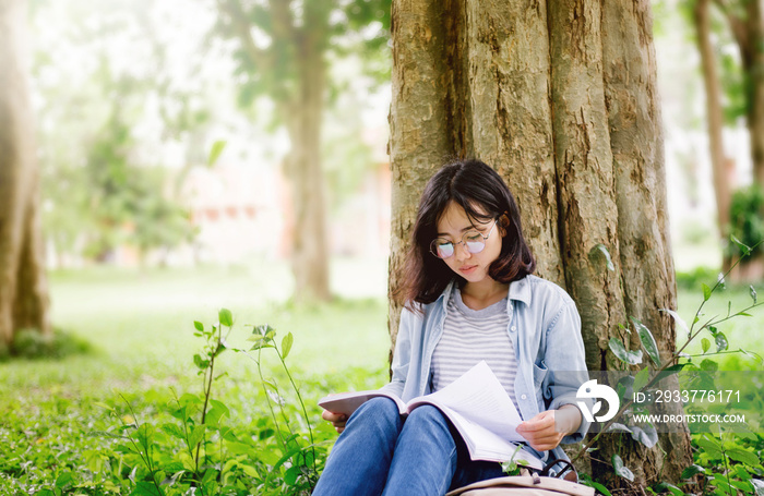 young woman reading a book in park