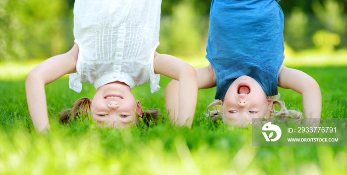 Happy children playing head over heels on green grass