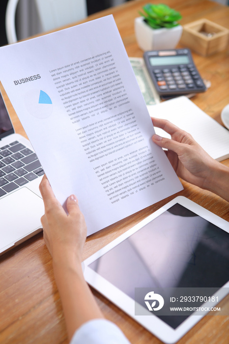 Business woman reading business news with laptop and stationery on wooden desk