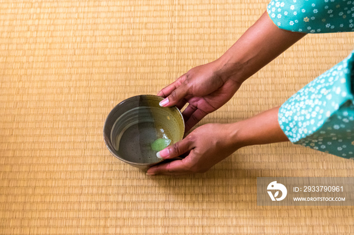 非裔美国女性客人手拿茶碗里的抹茶给日本女性，茶桅杆