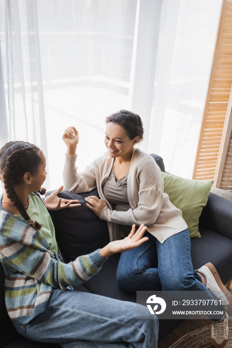 high angle view of african american girl gesturing during conversation with smiling mom at home