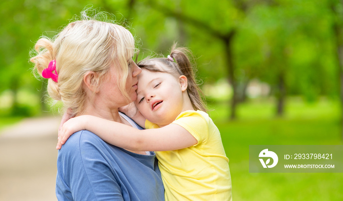 Happy family. Mom and her little daughter with syndrom down have a fun in summer park. Empty space f