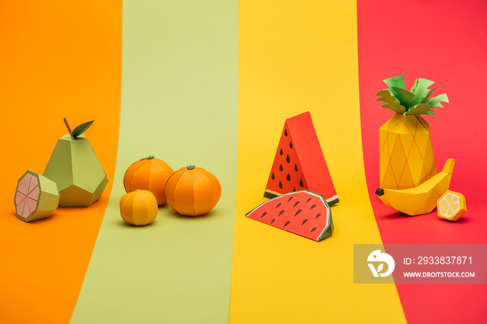 Various handmade origami fruits on stripes of colorful paper