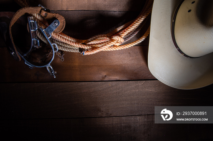 American Cowboy Items incluing a lasso spurs and a traditional straw hat on a wood plank background