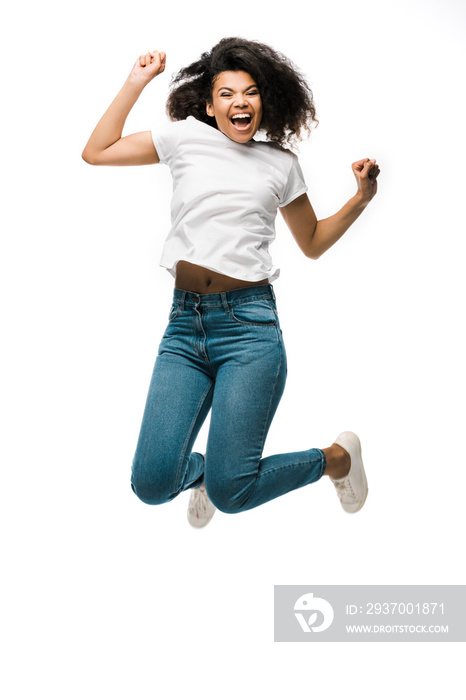 happy african american woman gesturing while celebrating and jumping isolated on white