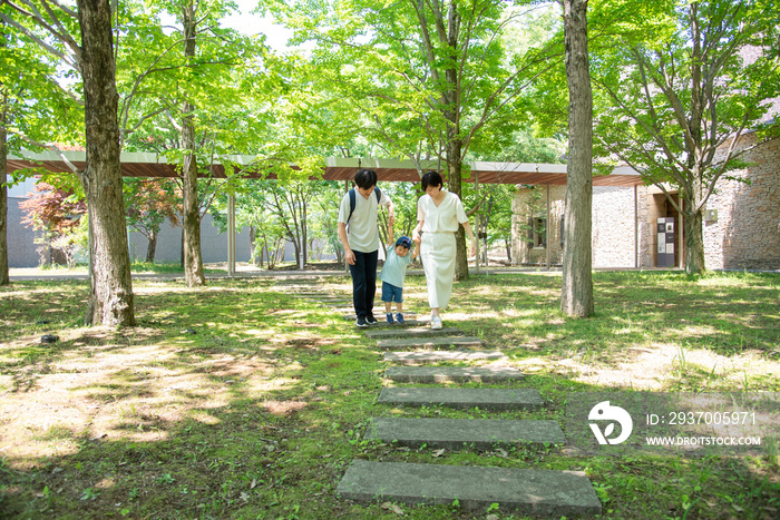 緑の中、手を繋いで歩く家族