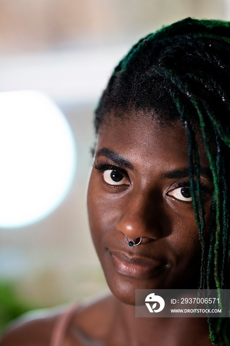 Black woman with green dreadlocks staring and smiling