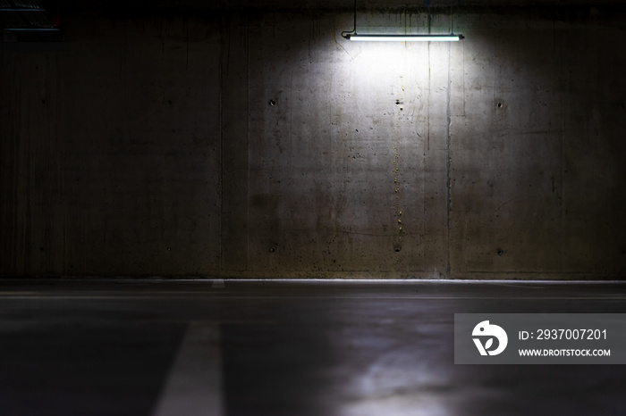 Empty parking lot with overhead dim light, underground parking garage.