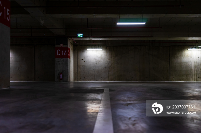 Empty parking lot with overhead dim light, underground parking garage.