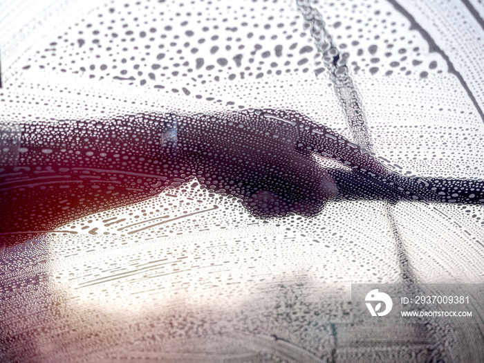 Windshield washing. Staff using squeegee cleaning the windshield.