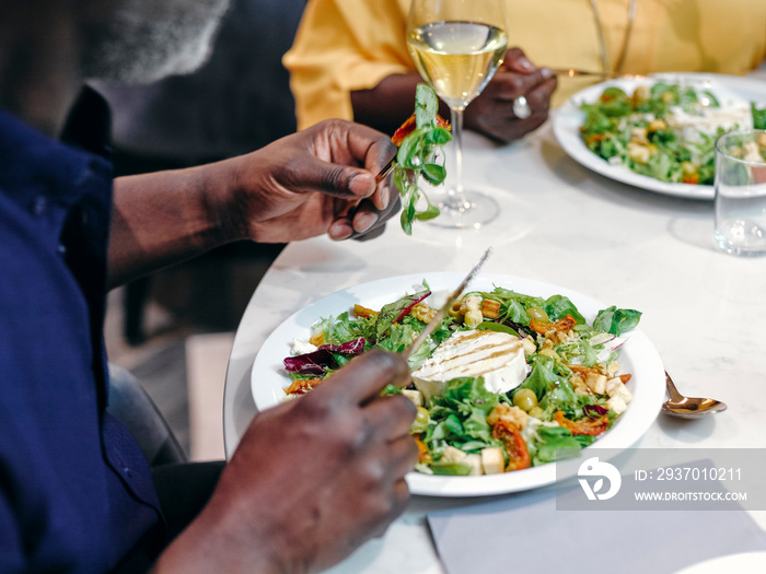 UK, Close-up of mature couple eating salads at restaurant table