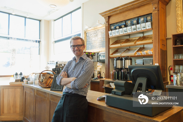 Coffee shop owner leaning against front counter