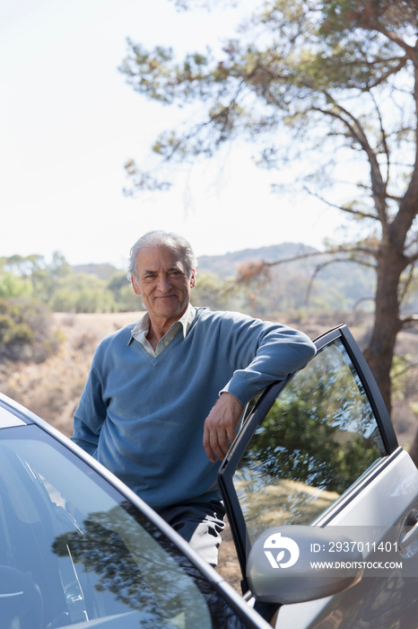 Portrait confident senior man standing outside car at roadside