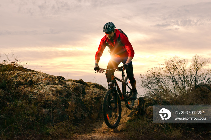 Cyclist in Red Riding Bike on the Autumn Rocky Trail at Sunset. Extreme Sport and Enduro Biking Conc