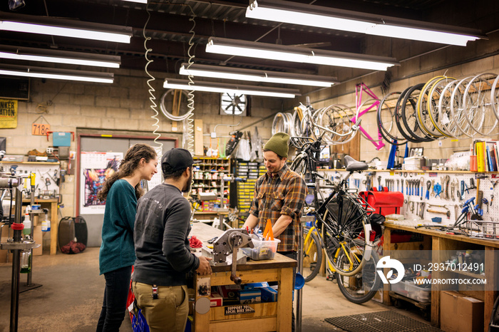 Mid-adult man talking with customers in bicycle shop