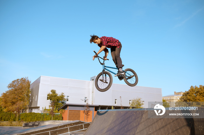 Male bmx biker jumps on ramp in skatepark