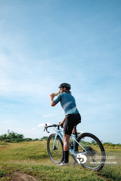 A young bearded cyclist is biking through a field