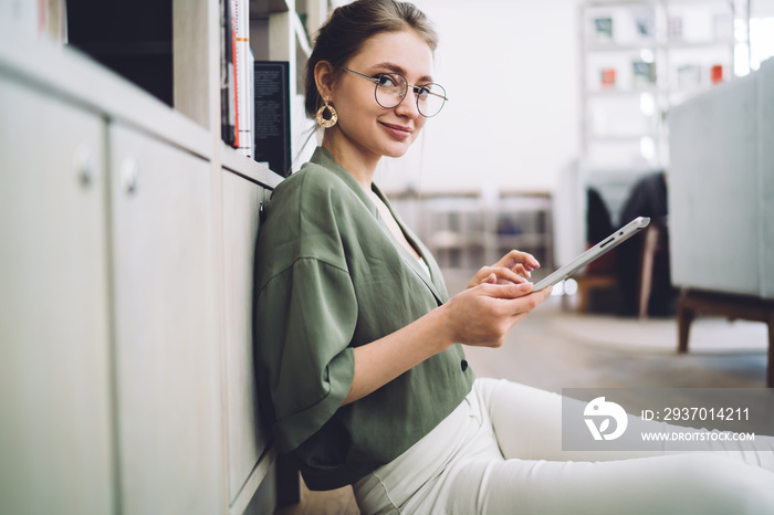 Cheerful woman looking at camera while using tablet