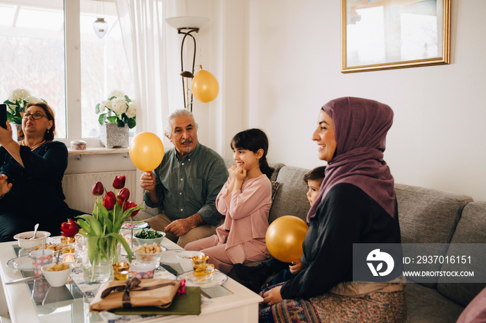 Excited family sitting on sofa during party at home