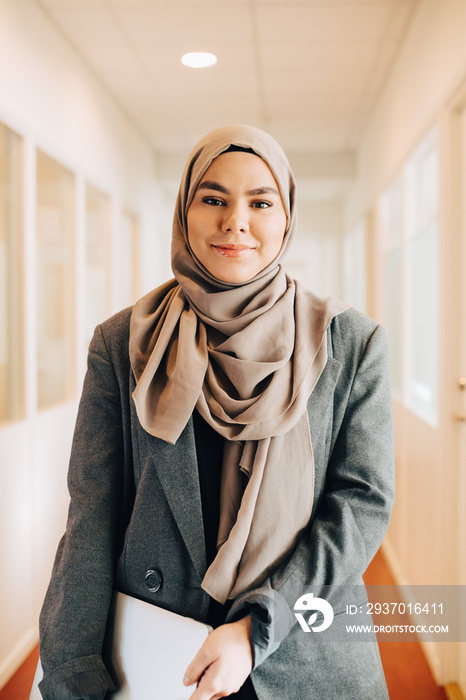 Portrait of confident female executive standing at office corridor