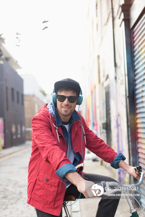 Smiling man with headphones and sunglasses on bicycle