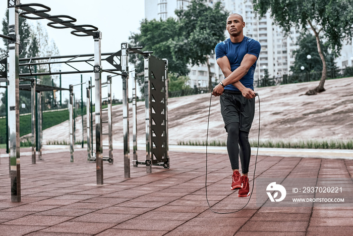 Muscular african man is skipping rope. Portrait of muscular young man exercising