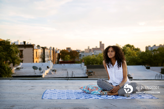 Woman sitting on blanket on rooftop