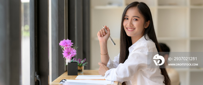 快乐的女大学生坐在咖啡馆准备考试的侧视图