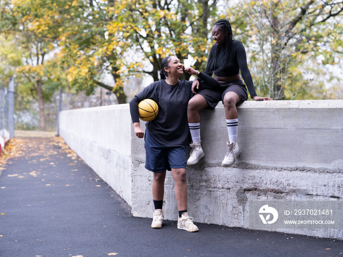 Two female friends outdoors holding basketball ball