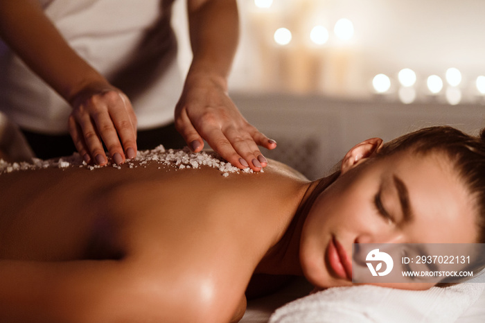 Woman getting salt scrub treatment in the spa