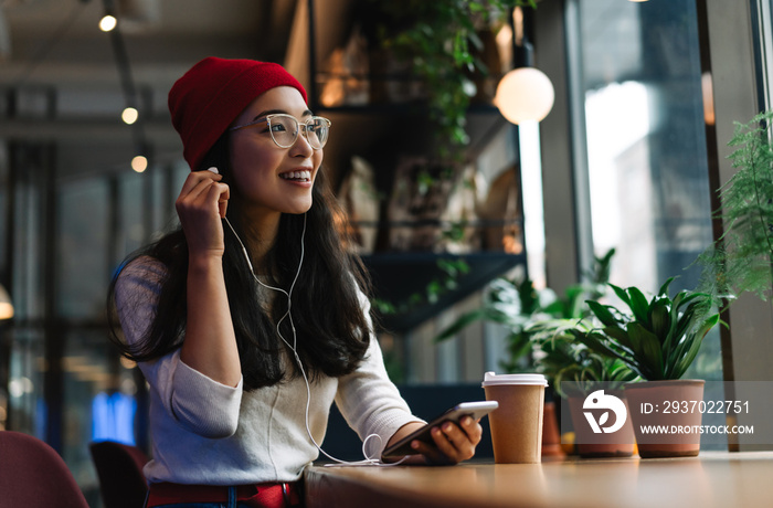 Smiling, positive asian woman with beautiful emotional face wearing eyeglass listening to music in c